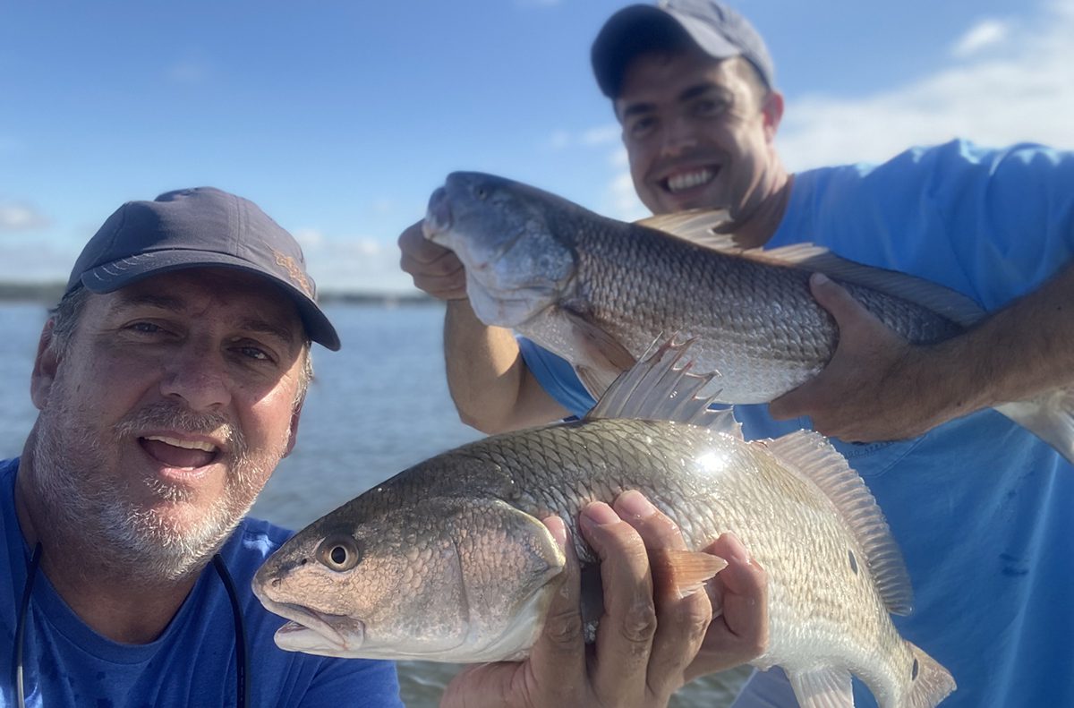 Red drum love the chase shrimp in shallow creeks where Josh Helms, right, of New Bern found them feeding with gusto while on a trip with the author.
