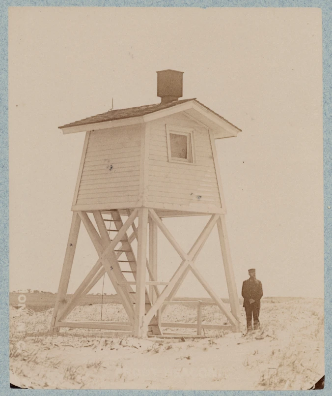 A keeper standing next to the Oak Island Range Light (front light), 1894. Source: Records of the U.S. Coast Guard (RG 26), National Archives- College Park (#45698276)