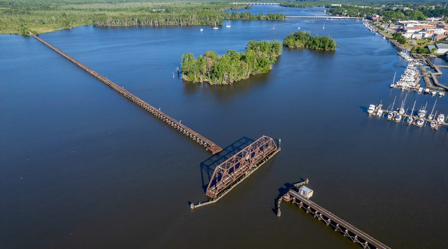 The Coastal Railway Swing Bridge spans the Pamlico River in Washington, where the waterfront can be seen on the north bank at upper right in this recent image. Farther in the distance are the U.S. Highway 17 Business bridge into town and, beyond it, the U.S. 17 Bypass. Photo: Dylan Ray