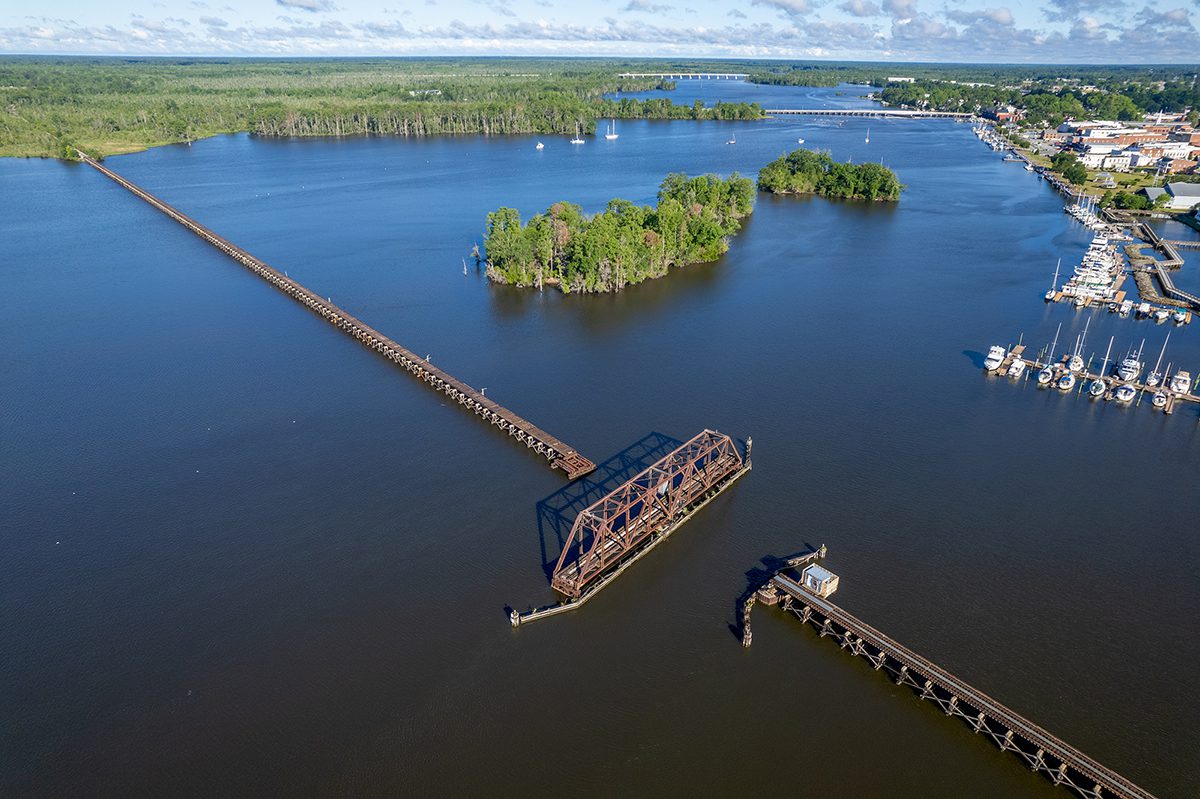 The Coastal Railway Swing Bridge spans the Pamlico River in Washington, where the waterfront can be seen on the north bank at upper right in this recent image. Farther in the distance are the U.S. Highway 17 Business bridge into town and, beyond it, the U.S. 17 Bypass. Photo: Dylan Ray