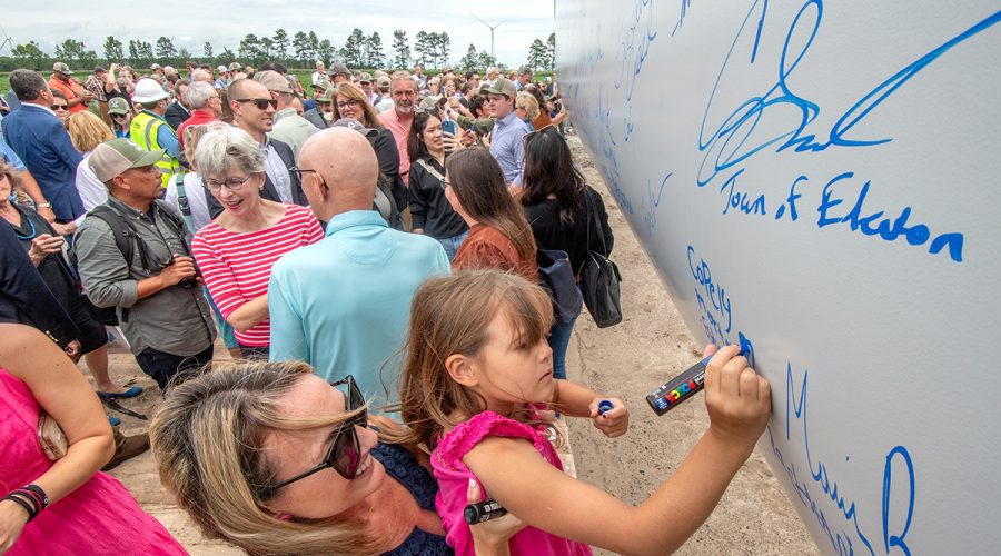 Copely Morton-Estes, right, is lifted up by her mother Rachel Estes as she and others from the area add their autographs to a wind turbine blade Wednesday at Timbermill Wind near Edenton. Photo: Dylan Ray