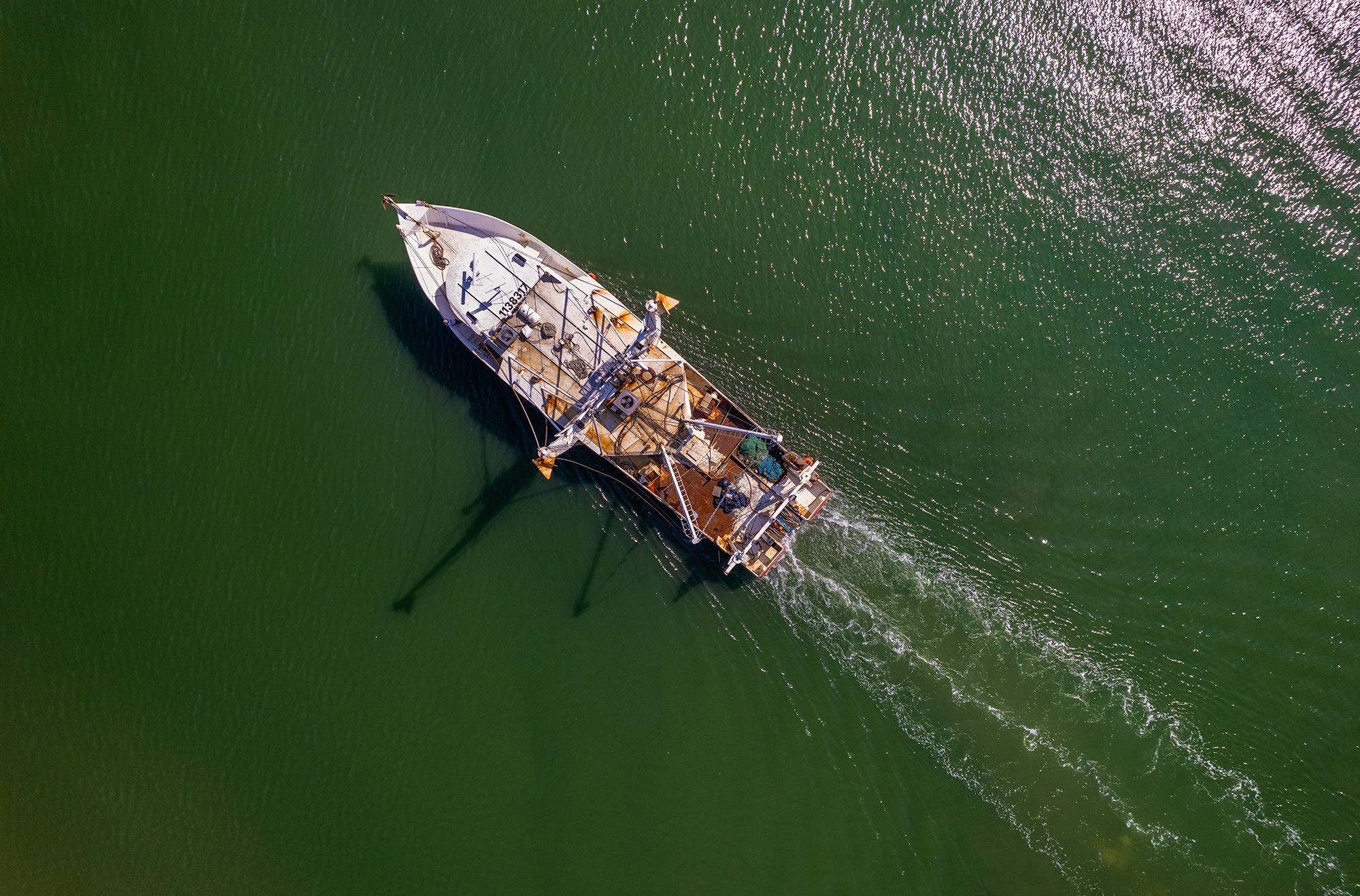 A commercial fishing trawler glides over the shallow waters of Gallants Channel near Pivers Island in Beaufort. Photo: Dylan Ray