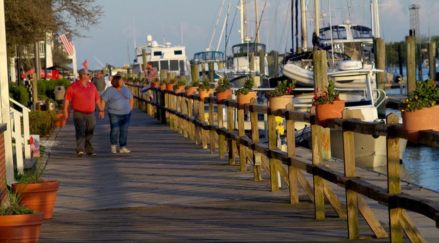 Couples stroll the Beaufort waterfront boardwalk in April, glancing toward the docks on Taylors Creek and the Rachel Carson Reserve just beyond. Photo: Mark Hibbs