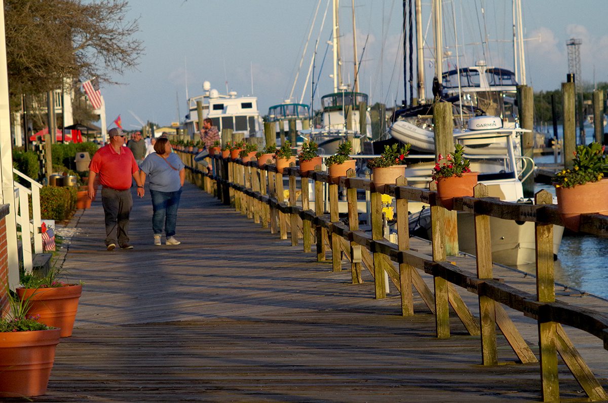 Couples stroll the Beaufort waterfront boardwalk in April, glancing toward the docks on Taylors Creek and the Rachel Carson Reserve just beyond. Photo: Mark Hibbs
