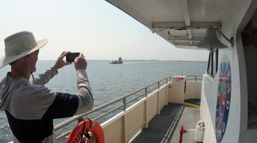 A rider on the Bald Head Island passenger Ferry snaps a photo of a Bald Head Island vehicle ferry as the two vessels near one another just off Southport in July. Photo: Mark Courtney