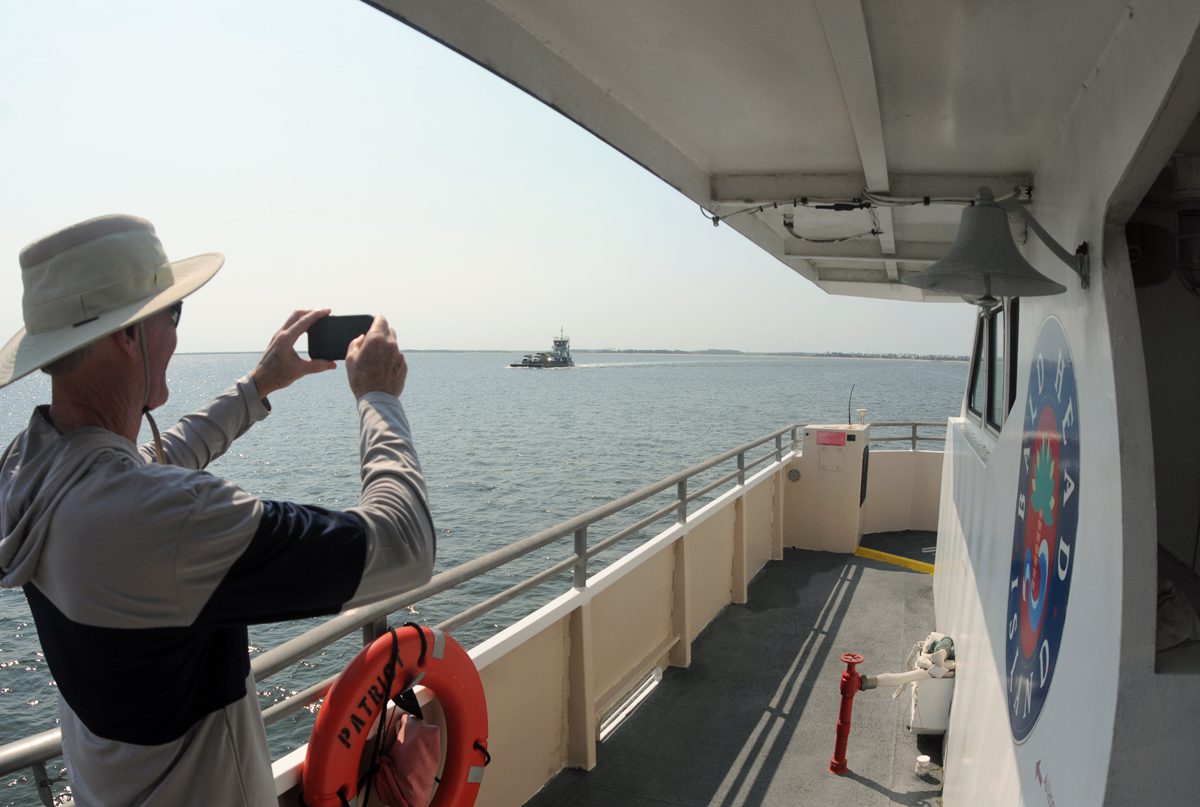 A rider on the Bald Head Island passenger Ferry snaps a photo of a Bald Head Island vehicle ferry as the two vessels near one another just off Southport in July. Photo: Mark Courtney