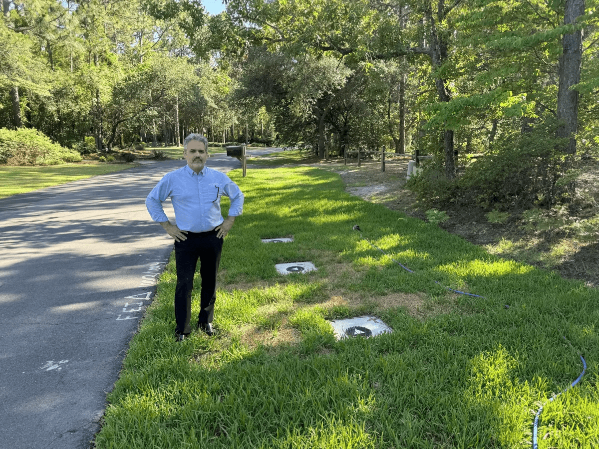 Wilmington resident Steve Schnitzler stands next to the caps for three monitoring wells installed by Chemours to monitor PFAS contamination in his neighborhood's groundwater. In 2023, Schnitzler's drinking water well was tested, and the results showed PFAS levels that exceeded the EPA's drinking water health advisory. Per the consent order requirements, Chemours covered the cost of four reverse osmosis water filtration systems installed in his home. Photo: Will Atwater
