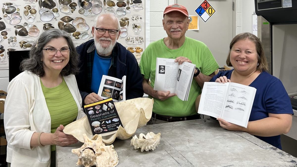 From left, Katie Mosher, Art Bogan, Ed Shuller and Erika Young hold copies of the newly revised "Seashells of North Carolina" holding their copies of the new book while visiting Bogan at the North Carolina Museum of Natural Sciences' Prairie Ridge Ecostation in Raleigh. Photo: North Carolina Sea Grant