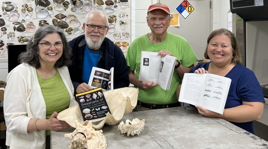 From left, Katie Mosher, Art Bogan, Ed Shuller and Erika Young hold copies of the newly revised "Seashells of North Carolina" holding their copies of the new book while visiting Bogan at the North Carolina Museum of Natural Sciences' Prairie Ridge Ecostation in Raleigh. Photo: North Carolina Sea Grant