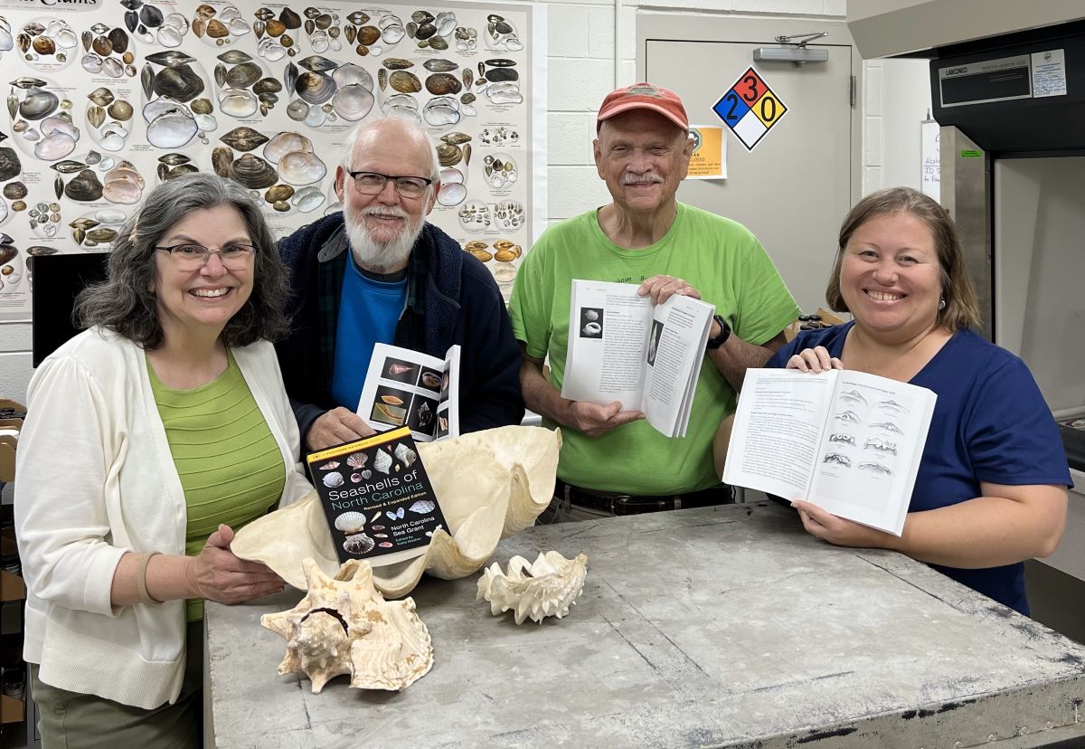 From left, Katie Mosher, Art Bogan, Ed Shuller and Erika Young hold copies of the newly revised "Seashells of North Carolina" holding their copies of the new book while visiting Bogan at the North Carolina Museum of Natural Sciences' Prairie Ridge Ecostation in Raleigh. Photo: North Carolina Sea Grant