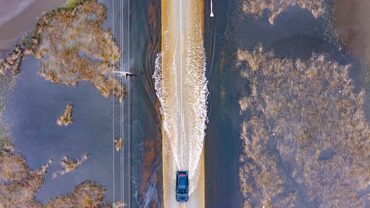 A vehicle creates a wake Tuesday while passing through floodwaters from the saltmarsh along Crow Hill Road near Otway in Down East Carteret County. Carteret County and coastal Onslow County were placed under a coastal flood advisory Tuesday effective until 5 p.m. Wednesday. Up to a foot of inundation above ground level is possible in low-lying areas near shorelines and tidal waterways. Officials urge people not to drive through waters of unknown depths. Photo: Dylan Ray