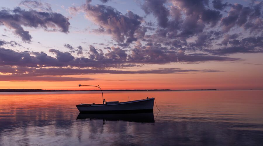 A fishing skiff anchored at the North River Bridge in Otway, in Carteret County, is nearly silhouetted at dawn recently. Photo: Doug Waters