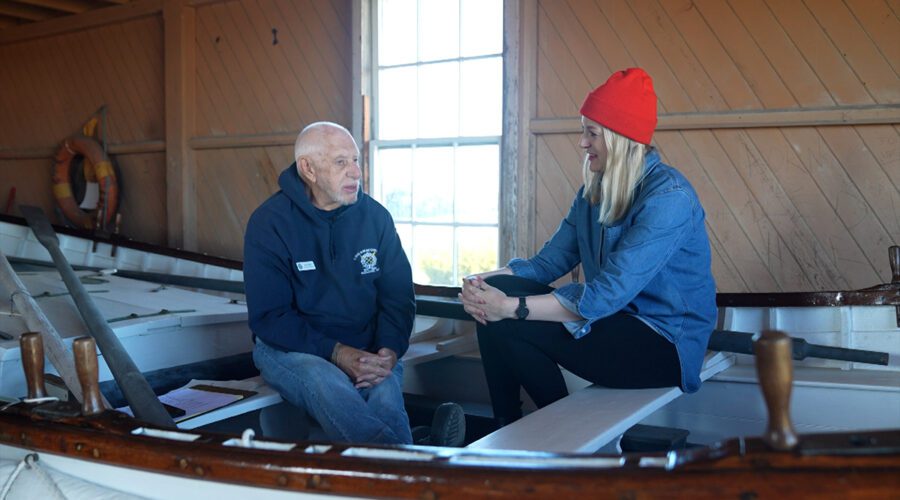 Chicamacomico Historic Site Executive Director John Griffin is interviewed by PBS director and producer, Rebecca Ward in Surfboat No. 1046, which was used in the Mirlo rescue. Photo: PBS-NC