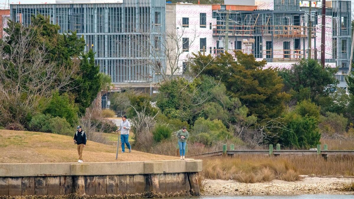 Visitors recently stroll along the water's edge at Cedar Street Park in downtown Beaufort, the construction site of Compass Hotel Beaufort by Margaritaville Resorts in the background. The hotel on Cedar Street is scheduled to open in 2025. Photo: Dylan Ray