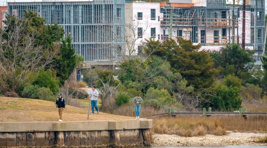 Visitors recently stroll along the water's edge at Cedar Street Park in downtown Beaufort, the construction site of Compass Hotel Beaufort by Margaritaville Resorts in the background. The hotel on Cedar Street is scheduled to open in 2025. Photo: Dylan Ray