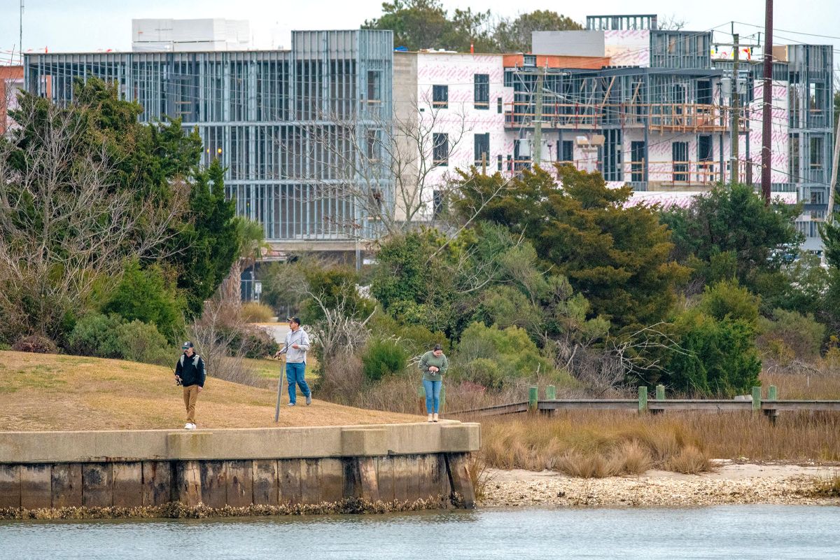 Visitors recently stroll along the water's edge at Cedar Street Park in downtown Beaufort, the construction site of Compass Hotel Beaufort by Margaritaville Resorts in the background. The hotel on Cedar Street is scheduled to open in 2025. Photo: Dylan Ray