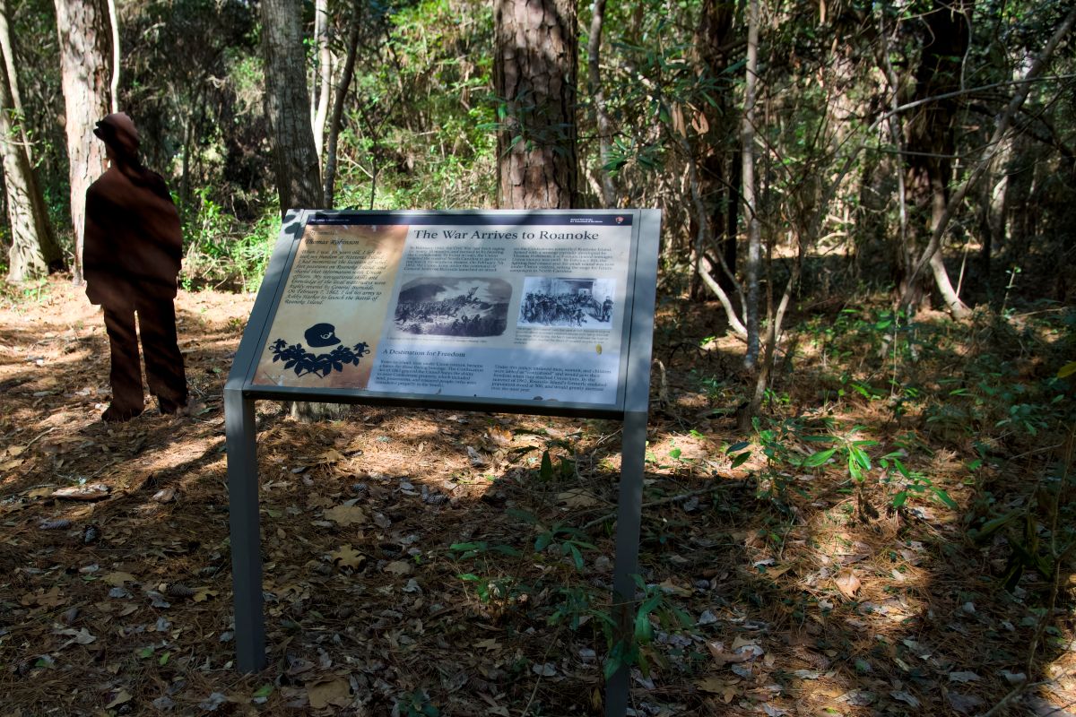 The sign "The War Arrives to Roanoke" and silhouette representing Thomas Robinson, who helped the Union Army, along the Freedom Trail at Fort Raleigh National Historic Site. Photo: Kip Tabb