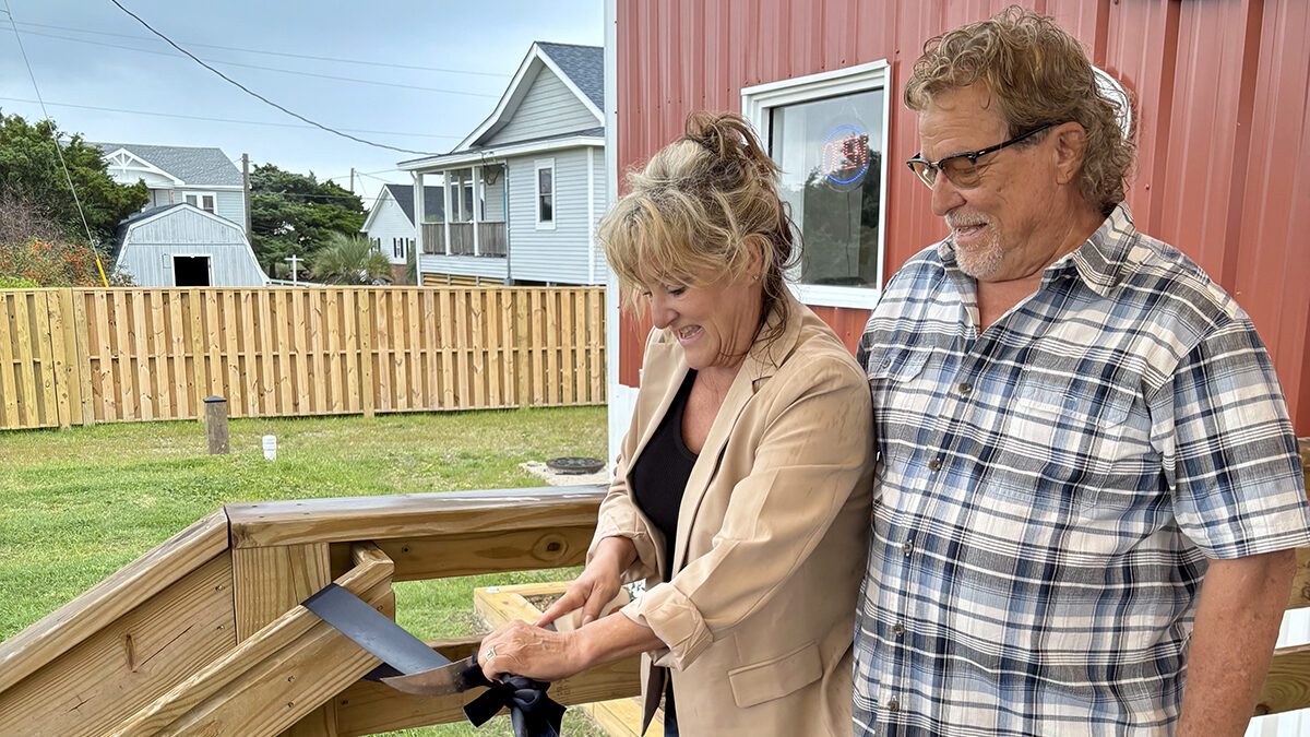 Jeffrey Aiken, right, stands with Mary Ellon Ballance, as she uses a fileting knife during the ribbon-cutting celebration May 21 for Jeffrey's Seafood's official opening. Photo: Lynne Foster
