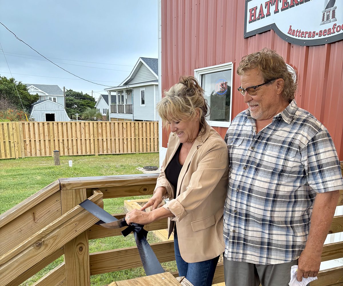 Jeffrey Aiken, right, stands with Mary Ellon Ballance, as she uses a fileting knife during the ribbon-cutting celebration May 21 for Jeffrey's Seafood's official opening. Photo: Lynne Foster