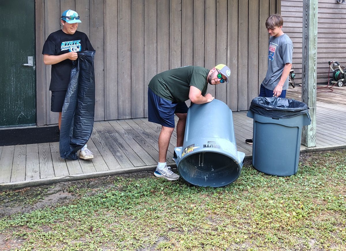 Volunteers, from left, Liam Calabria, Nick Davies, and Jackson Saunders, best friends from Raleigh, ready trash cans July 3 ahead of the Core Sound Waterfowl Museum and Heritage Center All American Shrimp Fry that took place July 5. Photo: Jennifer Allen