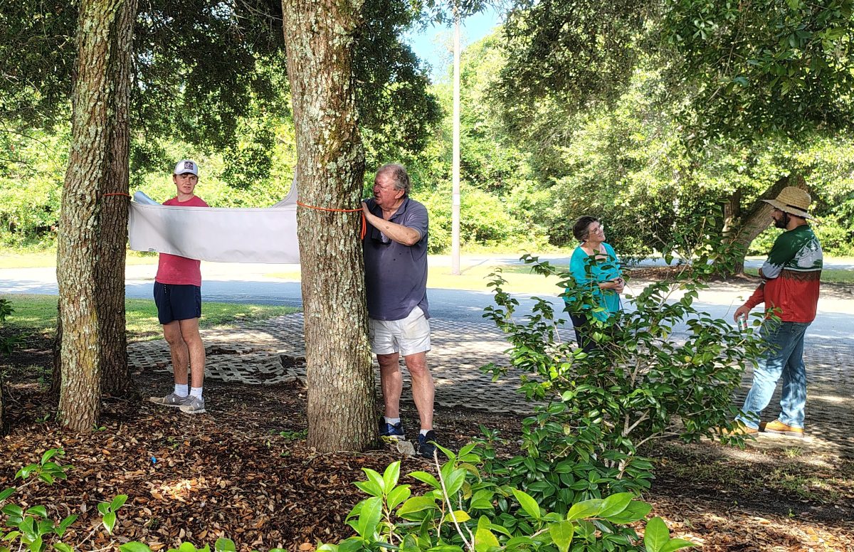 High school senior Thomas Lathan, left, and his grandfather Bill Lathan hang up a sign July 3 on the museum grounds as Executive Director Karen Amspacher speaks to a volunteer. Photo: Jennifer Allen