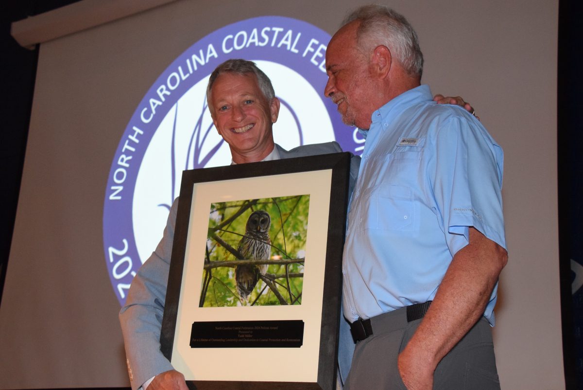 North Carolina Coastal Federation Executive Director Braxton Davis, left, presents an award to the organization's founder and former executive director, Todd Miller, during the 2024 Pelican Awards ceremony in Joslyn Hall on the Carteret Community College campus. Photo: Mark Hibbs