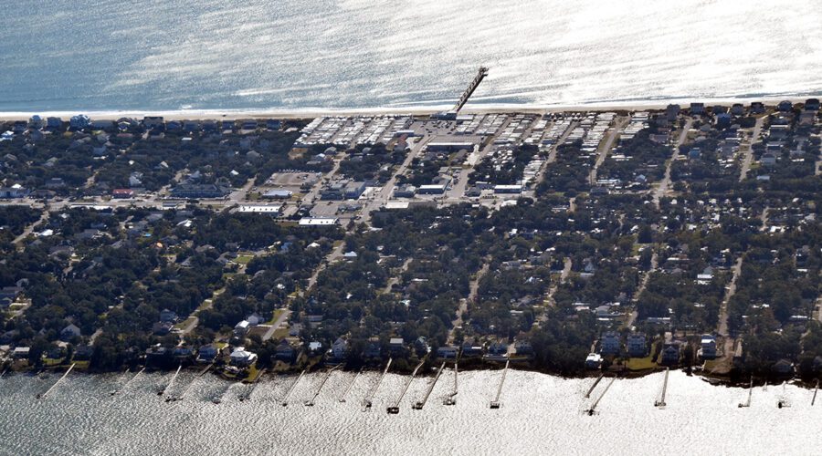 Sunlight reflects off the water where the Bogue Inlet Fishing Pier protrudes into the Atlantic Ocean and private piers extend into Bogue Sound in this 2021 aerial view of Emerald Isle on Bogue Banks in Carteret County. Photo: Mark Hibbs/Southwings