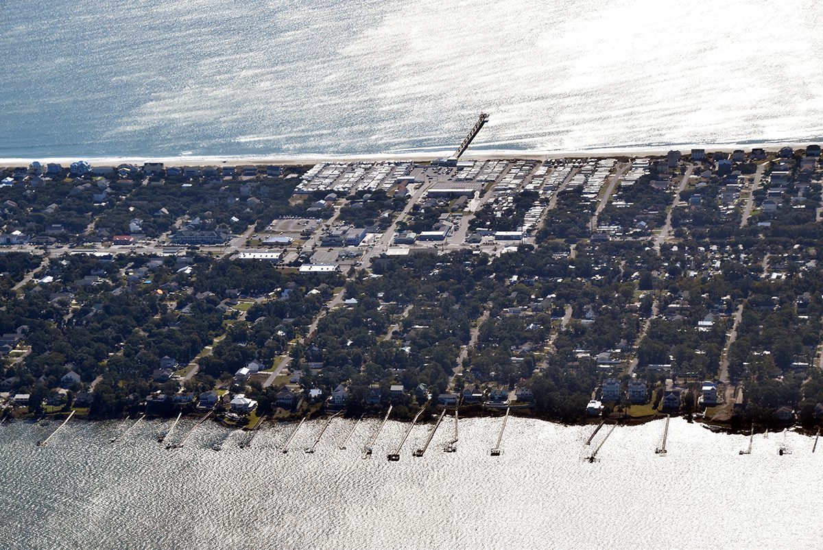 Sunlight reflects off the water where the Bogue Inlet Fishing Pier protrudes into the Atlantic Ocean and private piers extend into Bogue Sound in this 2021 aerial view of Emerald Isle on Bogue Banks in Carteret County. Photo: Mark Hibbs/Southwings