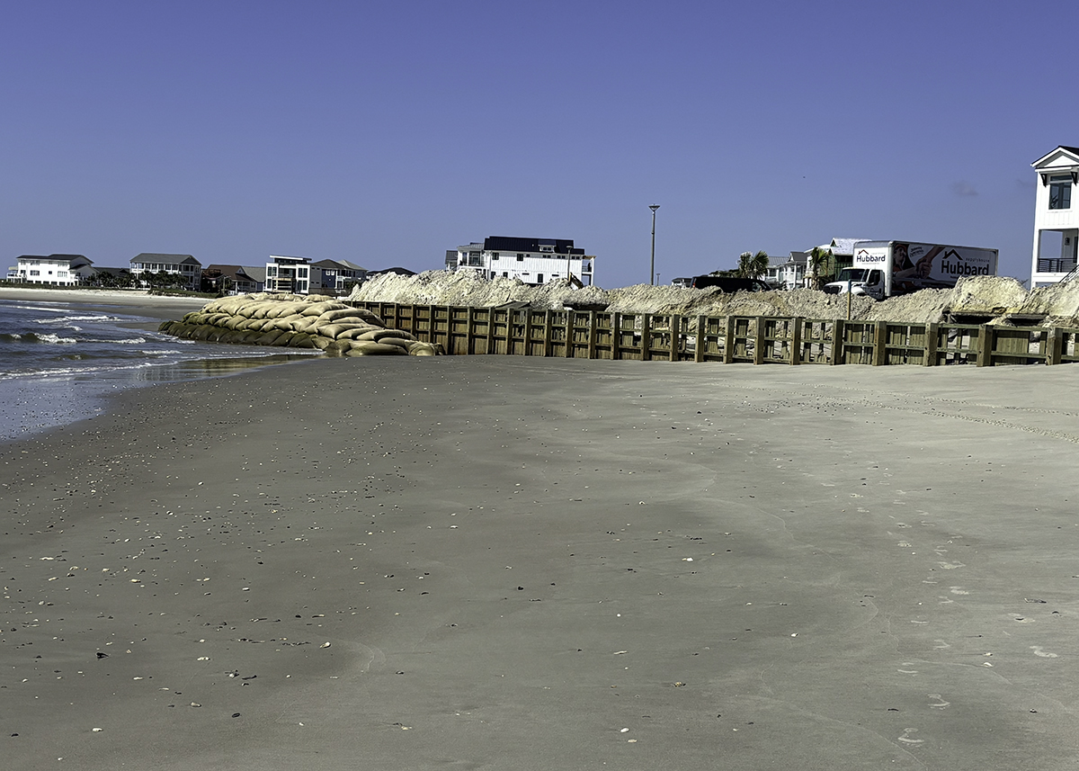 A wall of sandbags stretches in front of a wooden bulkhead that has been battered by waves as the ocean encroaches a new neighborhood built at the eastern end of Ocea Isle Beach. Photo: Trista Talton