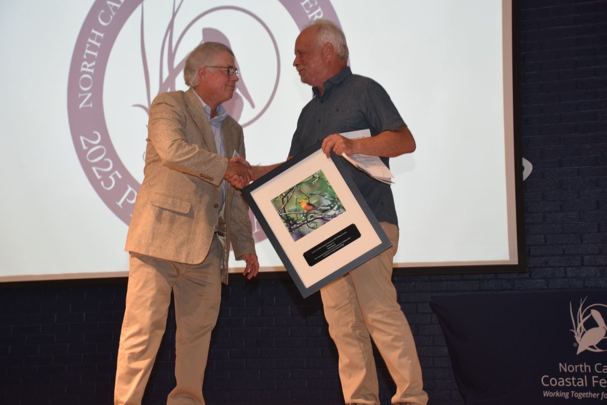 John Harris, left, accepts his Pelican Award from founder and senior adviser Todd Miller Saturday. Photo: Mark Hibbs