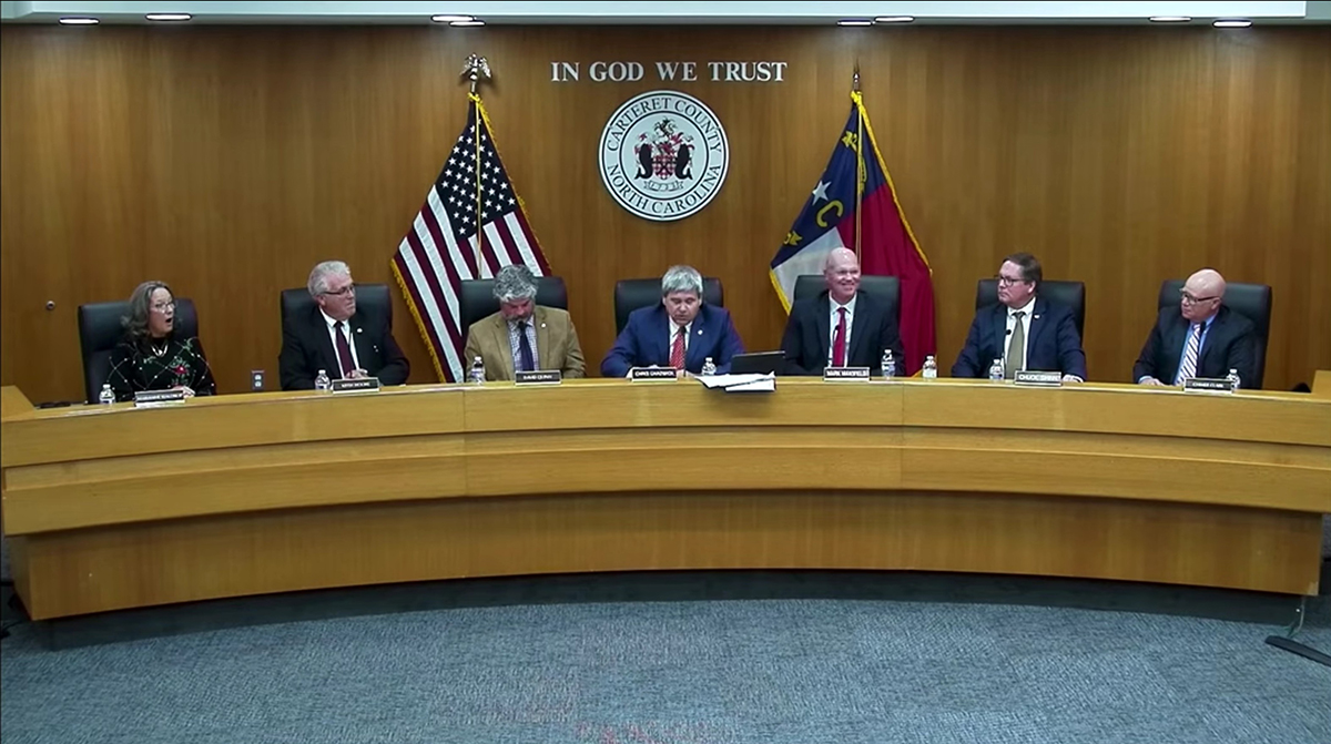 Carteret County Commissioner Marianne Waldrop, far left, visibly reacts to Chairman Chris Chadwick, center, as he refuses to acknowledge Hanukkah in his holiday wishes.