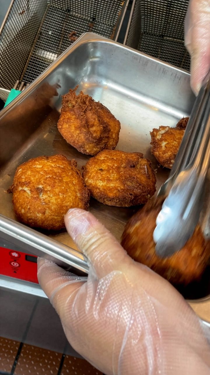 Sharon Peele Kennedy’s son, Jeffrey Kennedy, pulls sizzling hot fish cakes out of the deep fryer during a March 2023 fundraiser for NC Catch at Basnight’s Lone Cedar Café in Nags Head. Photo: Liz Biro