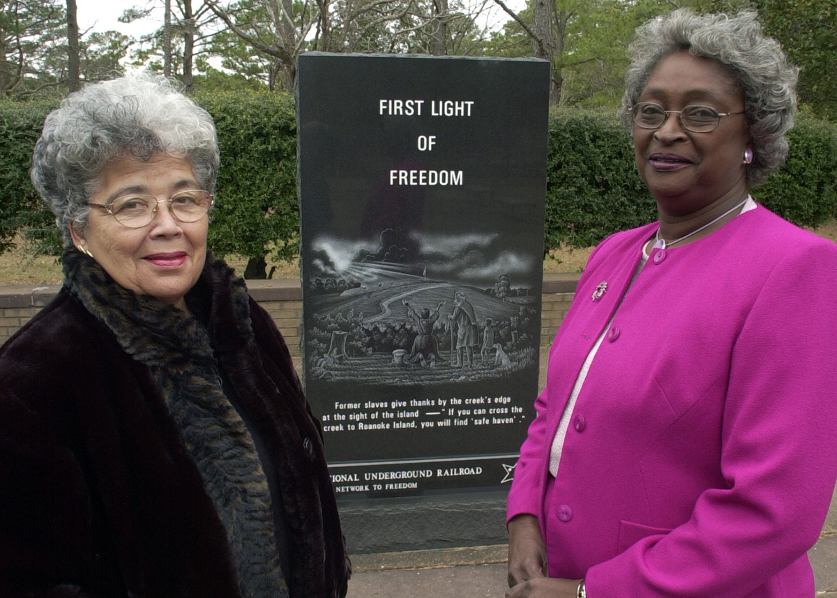 Former Manteo Commissioner Dellerva Collins, left, now deceased and whose vision was to open the Pea Island Cookhouse Museum poses with former Dare County Commissioner Virginia Tillett, also now deceased, at the First Light of Freedom Memorial unveiling in 2001. “Dell” as Collins was best known, played a key role resulting in the placement of this memorial at the National Park Service - Fort Raleigh site. Because of  her leadership, in 2006 the original cookhouse building once located at the Pea Island station was moved to Roanoke Island and renovated as a museum. Photo: Drew Wilson
