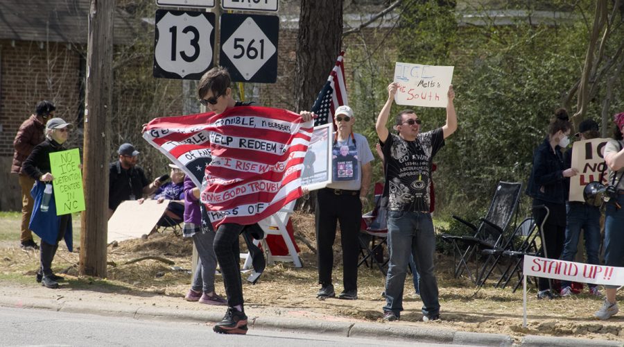 Melissa Stewart carries her flag of protest across the street Saturday in Ahoskie where as many as 40 demonstrated against plans for Immigration and Customs Enforcement to reopen the Rivers Correctional Facility in nearby Winton as a federal immigrant detention center. Photo: Kip Tabb