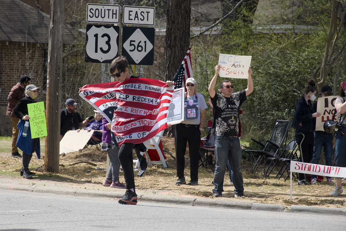 Melissa Stewart carries her flag of protest across the street Saturday in Ahoskie where as many as 40 demonstrated against plans for Immigration and Customs Enforcement to reopen the Rivers Correctional Facility in nearby Winton as a federal immigrant detention center. Photo: Kip Tabb