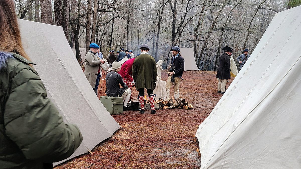 An attendee looks on as reenactors dressed in period costumes gather around a campfire during a battle commemoration program Feb. 27 at Moores Creek National Battlefield, which marked the 250th anniversary of the American patriots' first significant victory of the American Revolution. Photo: Jennifer Allen
