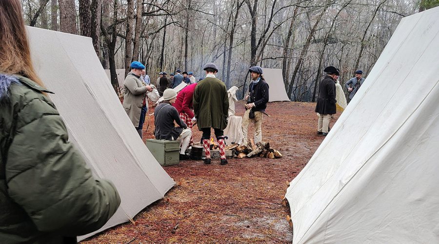 An attendee looks on as reenactors dressed in period costumes gather around a campfire during a battle commemoration program Feb. 27 at Moores Creek National Battlefield, which marked the 250th anniversary of the American patriots' first significant victory of the American Revolution. Photo: Jennifer Allen