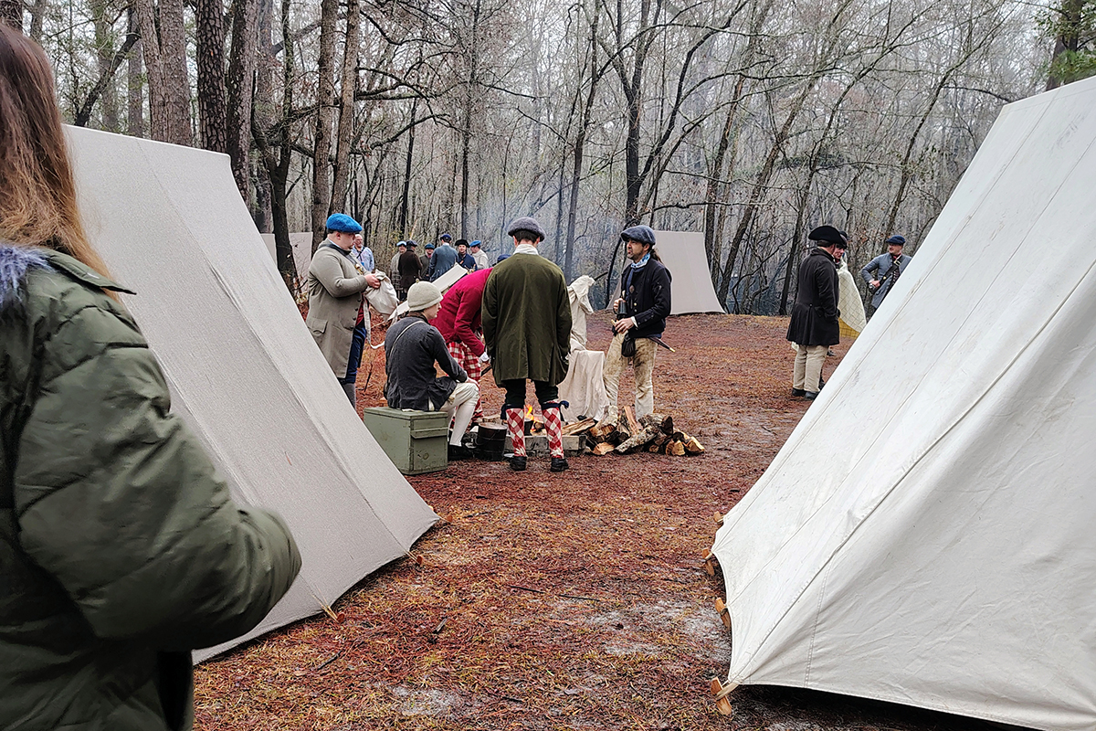 An attendee looks on as reenactors dressed in period costumes gather around a campfire during a battle commemoration program Feb. 27 at Moores Creek National Battlefield, which marked the 250th anniversary of the American patriots' first significant victory of the American Revolution. Photo: Jennifer Allen
