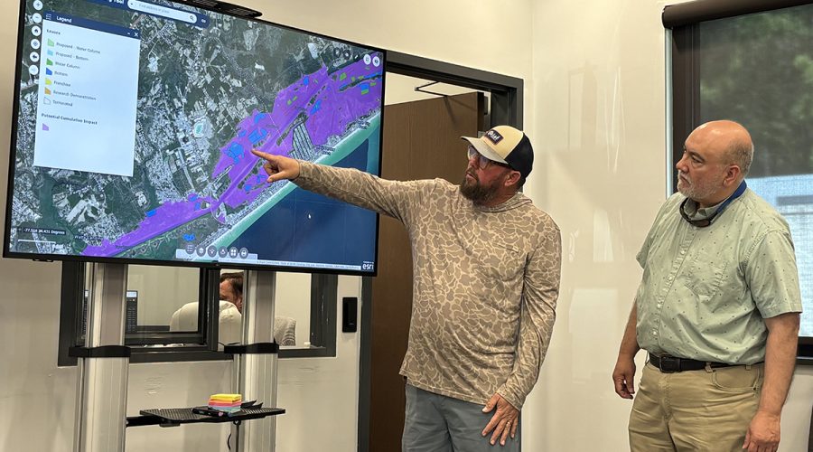 Fishing guide Capt. Ray Brittain, who has fished the waters around Topsail Island for more than three decades, points to a shellfish lease during a public forum in Surf City April 14. Photo: Trista Talton