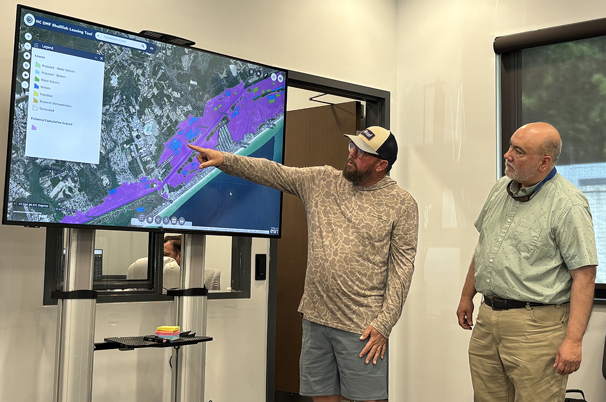 Fishing guide Capt. Ray Brittain, who has fished the waters around Topsail Island for more than three decades, points to a shellfish lease during a public forum in Surf City April 14. Photo: Trista Talton