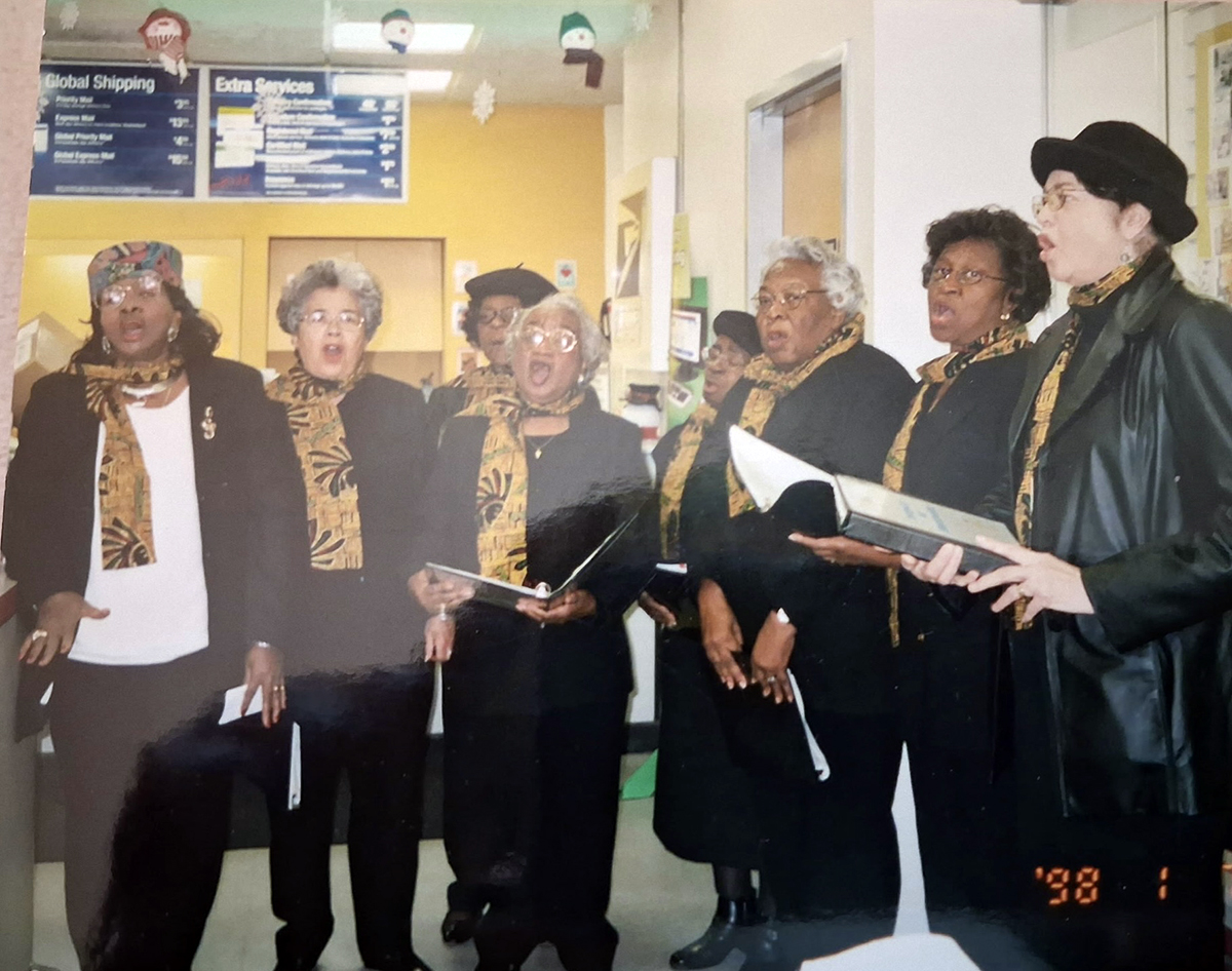 Eight of the original 12 Echoes, Directress Doris Creecy, Dellerva Collins, Annie Drake, Lovie Moore, Essie Lee Brown,  Mary McClease Conway, Elner Pierce and Arvilla Bowser, sing in 1998 at the Manteo Post Office.
