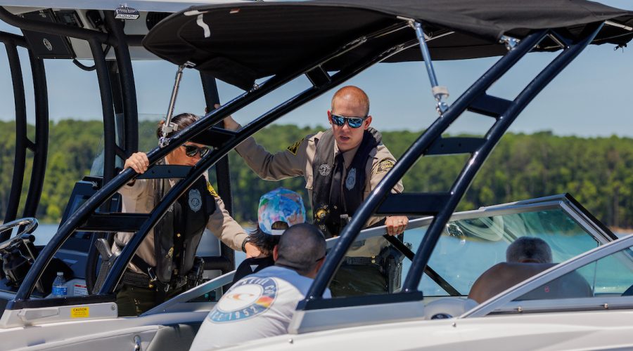 Officers Hannah Shively and Jake Thompson of the N.C. Wildlife Resources Commission Law Enforcement Division talk with boaters on Jordan Lake Tuesday, July 2, 2024. Photo: NCWRC