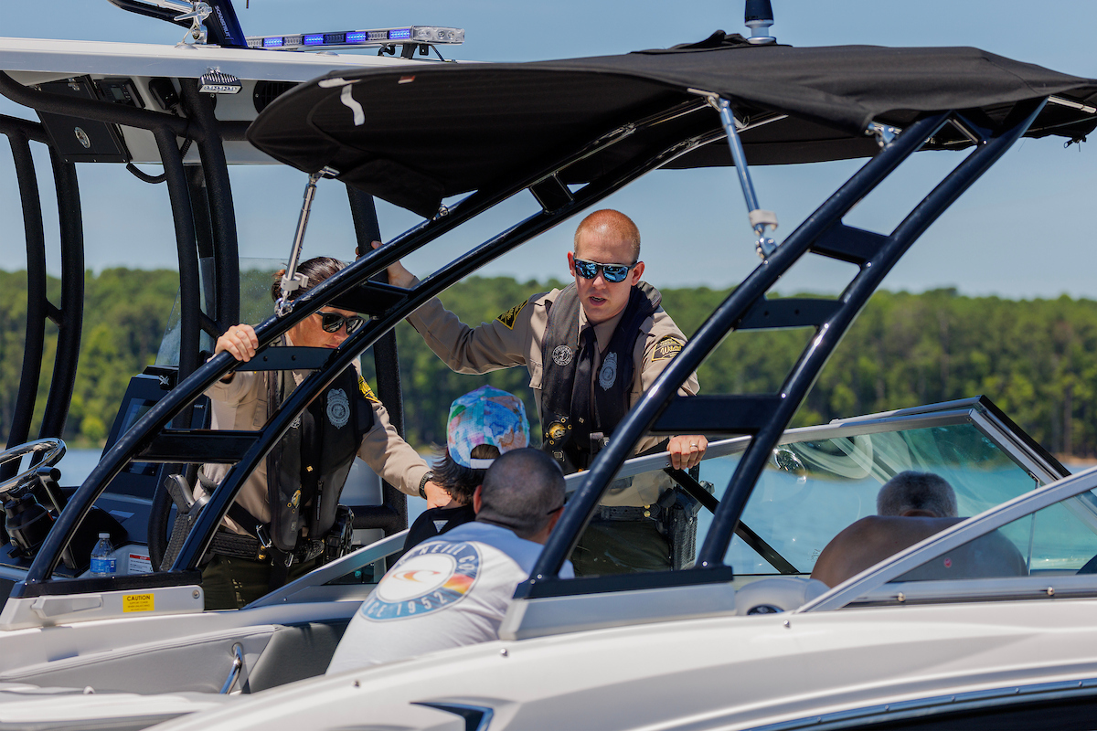 Officers Hannah Shively and Jake Thompson of the N.C. Wildlife Resources Commission Law Enforcement Division talk with boaters on Jordan Lake Tuesday, July 2, 2024. Photo: NCWRC