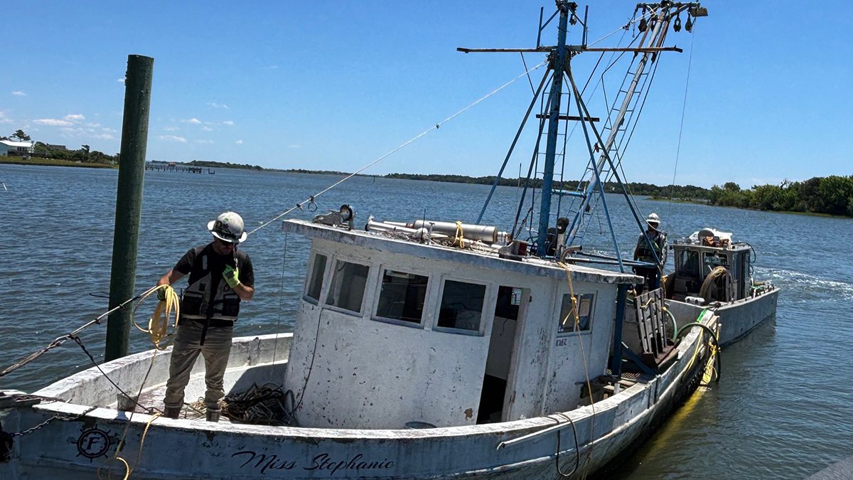 A crew with Mainstream Commercial Divers Inc. removes the Miss Stephanie, a dilapidated trawler, from a Sneads Ferry marina on Wednesday, June 3. The boat is one of 12 abandoned and derelict vessels being removed from North Carolina coastal waters by the North Carolina Coastal Federation. Photo: Trista Talton