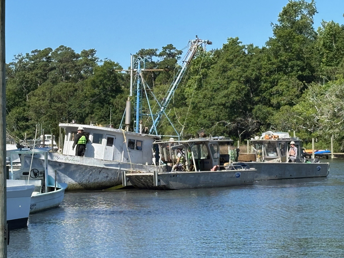 Mainstream Commercial Divers Inc. workers prepare to remove the Miss Stephanie, an abandoned trawler, from a marina in Sneads Ferry on Wednesday. Photo: Trista Talton