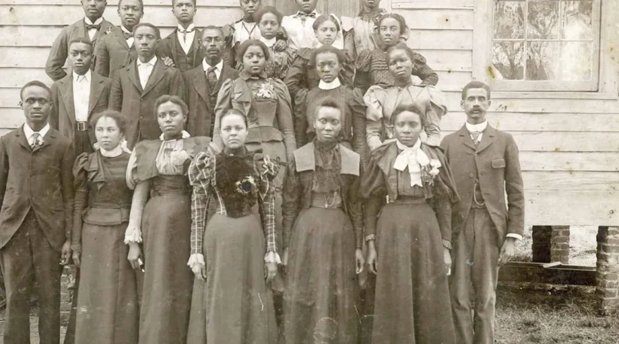 Principal Peter W. Moore, far right, and students of the Elizabeth City State Colored Normal School (later Elizabeth City State University) circa 1894. In the beginning, the school held classes in rented space at the Roanoke Institute, a private school sponsored by a black conference of Missionary Baptists. (Even earlier, a pioneering African American educator, Rooks Turner, had run a common school there.) Later, the State Colored Normal School moved to another temporary locale on what is now Herrington Road in Elizabeth City, then moved to its current home in 1912.