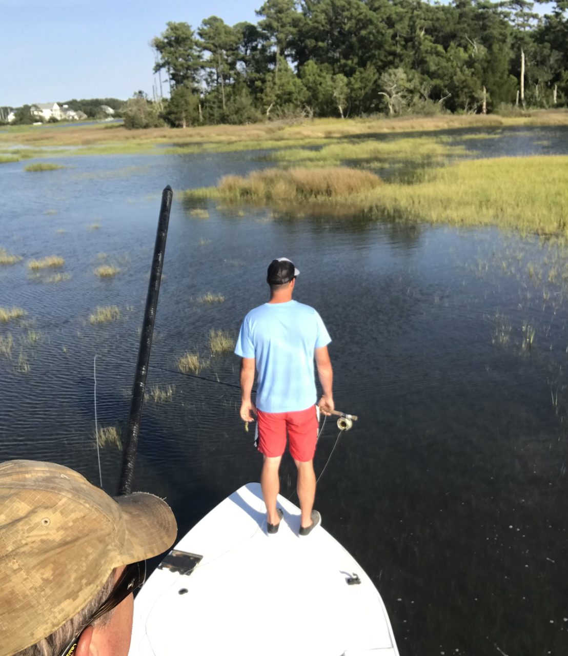 Capt. Gordon poles while Quentin Lehrschall scans for a possible fish in the backyards of some of the most expensive real estate in Carteret County. Photo: Gordon Churchill