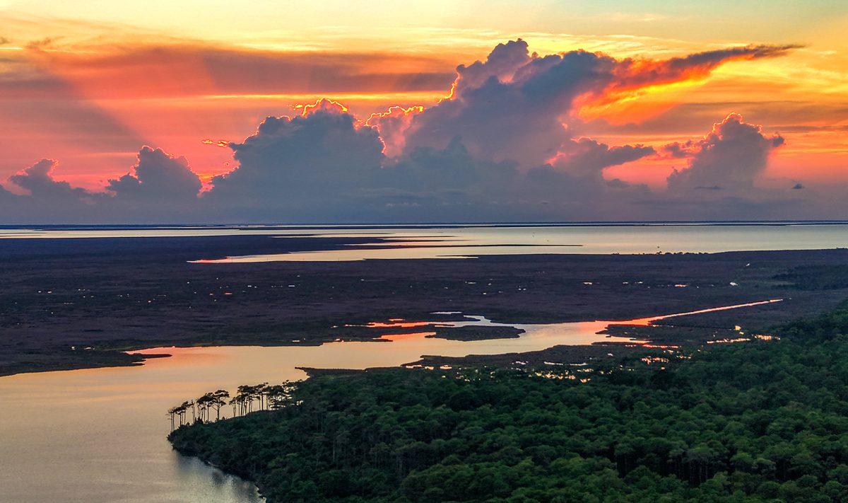 The sun sets behind a cloudbank Saturday as shown from above the Cedar Island National Wildlife Refuge. The refuge off Lola Road on Cedar Island in Carteret County was established in 1964 occupies 14,494 acres on a peninsula jutting into southern Pamlico Sound, with N.C. Highway 12 slicing through and the 5,500-acre Cedar Island National Wildlife Reserve just to the east. The refuge and the reserve both offer opportunities to immerse one's self into nature, such as hiking, paddling, birding and nature viewing, as well as numerous other activities. Photo: Dylan Ray