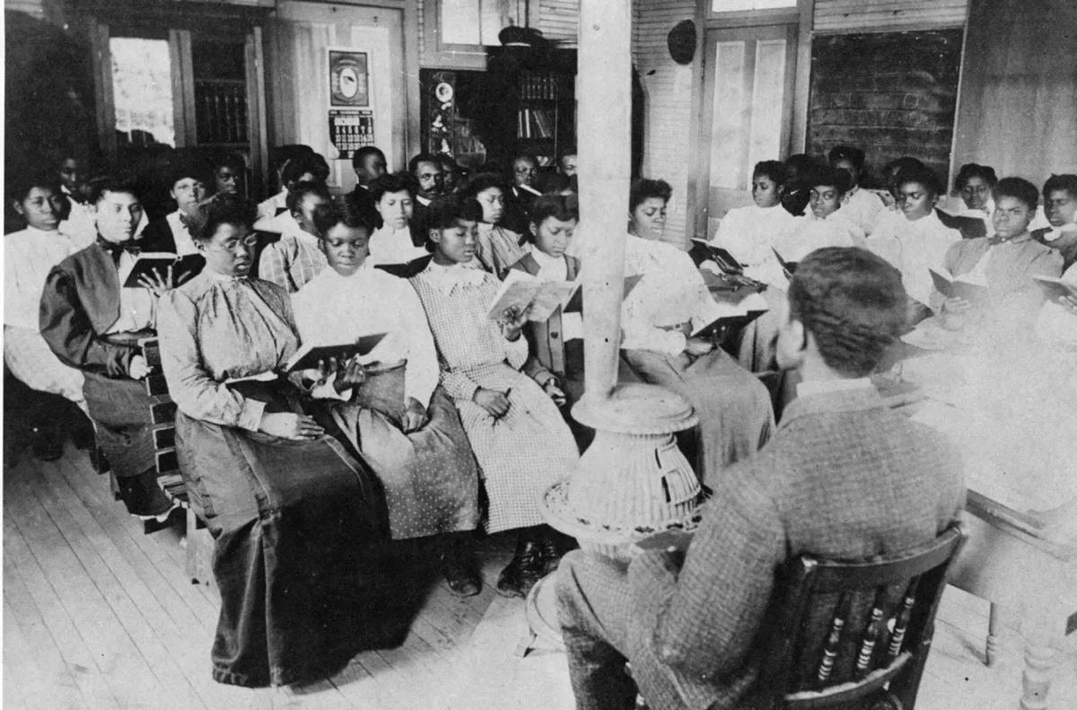 Dr. Moore and students at a class in one of the early temporary locations for the State Normal School, circa 1894-1911. Born near Faison in 1859, Moore had worked his way through Shaw University by tenant farming and working in a brickyard and foundry. After graduating from Shaw, he taught school in Bertie County, then served as assistant principal of the State Normal School in Plymouth, and was then named principal and first president of what is now Elizabeth City State University. Photo courtesy, University Archives, Elizabeth City State University