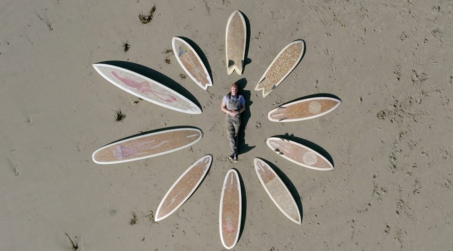 Film coproducer Taylor Lane poses with the 10 cigarette surfboards he created. Photo contributed.